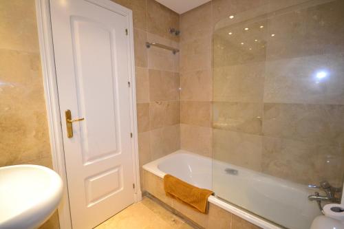a bathroom with a shower and a tub and a sink at marina duquesa 616 in Manilva