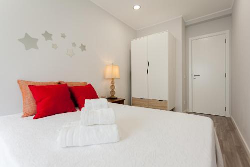 a bedroom with a white bed with red pillows at Apartamento da estação in Setúbal