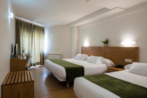 a hotel room with two beds and a television at Hotel Crisol de las Rías in Miño