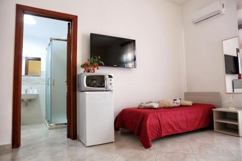 a room with a bed and a television on the wall at B&B Milena in Paceco