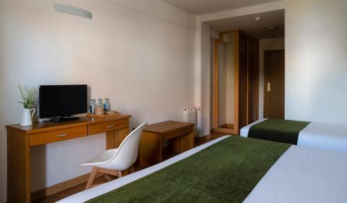 a hotel room with a bed and a desk with a television at Hotel Crisol de las Rías in Miño
