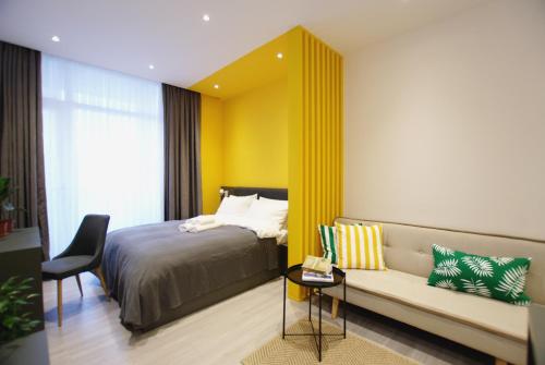 a bedroom with a bed and a couch and a chair at Banana Apartments in Batumi