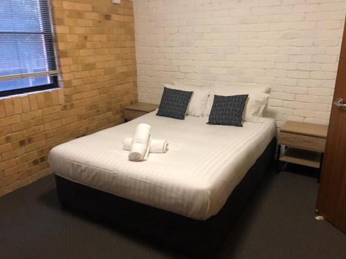 uma cama grande com lençóis brancos e almofadas em Alloggio Hanbury Mayfield em Newcastle