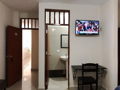 a bathroom with a toilet and a sink and a television on the wall at Estancia Real in Piura