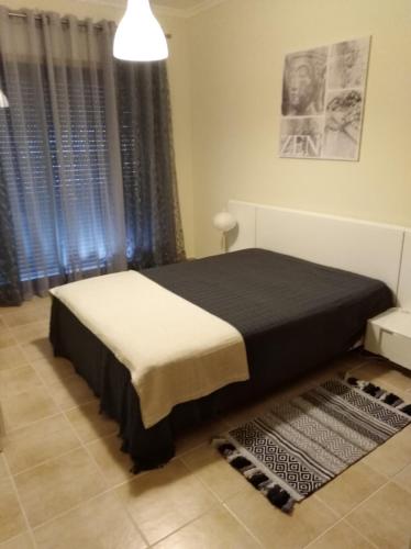 a bedroom with a bed with a black and white blanket at Alto dos Navegantes in Armação de Pêra