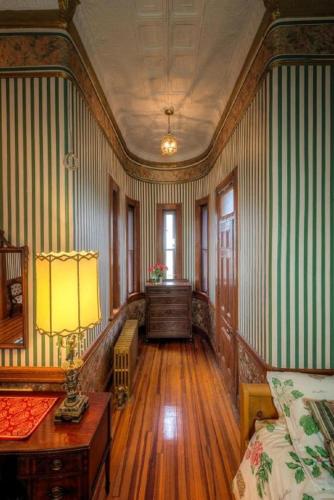 a room with green and white striped walls with a bed and a desk at Amsterdam Castle NY in Amsterdam