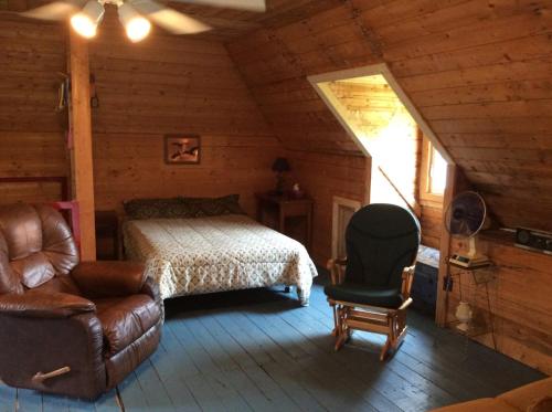 a bedroom with a bed and a chair in a cabin at Domaine Montauban in Saint Fortunat