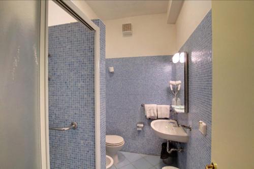 a blue tiled bathroom with a toilet and a sink at Hotel Guardacosta in Diamante