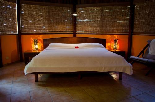 a bedroom with a large bed with two tables and two lamps at Hotel Vista de Olas in Santa Teresa Beach