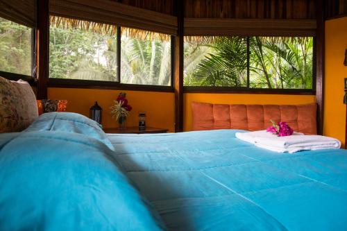 a blue bed in a room with windows at Hotel Vista de Olas in Santa Teresa Beach