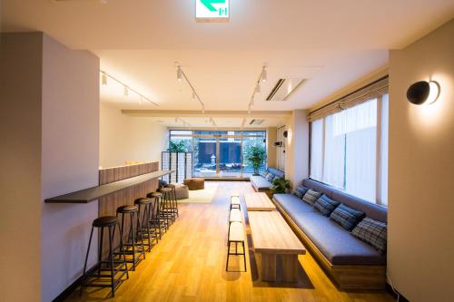 a living room with a long couch and a bar at Emblem Hostel Nishiarai in Tokyo