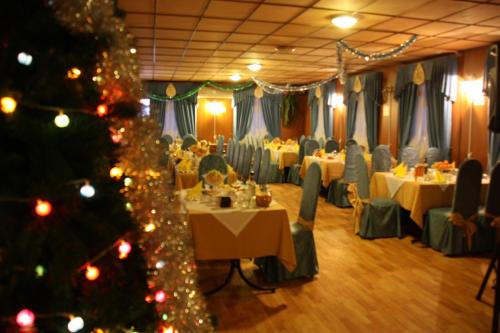 une salle à manger avec des tables et un sapin de Noël dans l'établissement Tourist Complex Botik, à Pereslavl-Zalesski