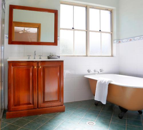 ein Badezimmer mit einer Badewanne, einem Waschbecken und einem Spiegel in der Unterkunft Berenbell Vineyard Retreat in Pokolbin