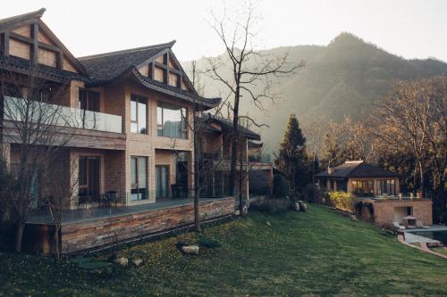 a house on a grassy yard with a mountain in the background at Evergreen Retreat-walk to National Forest Park, free pick up service in Zhangjiajie