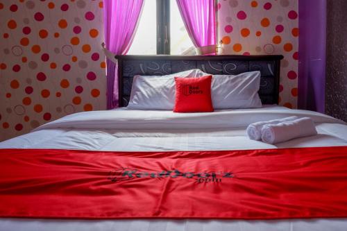 a bed with two red pillows on top of it at RedDoorz near RSUD Kebumen in Kebumen