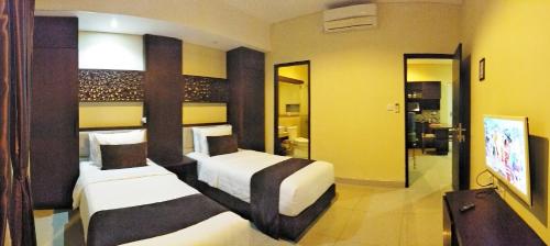 a hotel room with two beds and a bathroom at Maya Kori Villa in Jimbaran