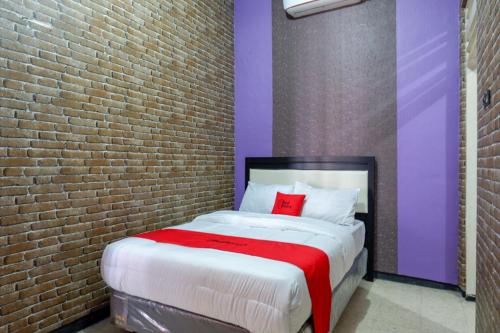 een slaapkamer met een groot bed met een bakstenen muur bij RedDoorz near Stasiun Kebumen in Kebumen