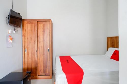 a bedroom with a bed and a wooden cabinet at RedDoorz Plus Syariah near Stasiun Tegal 2 in Tegal