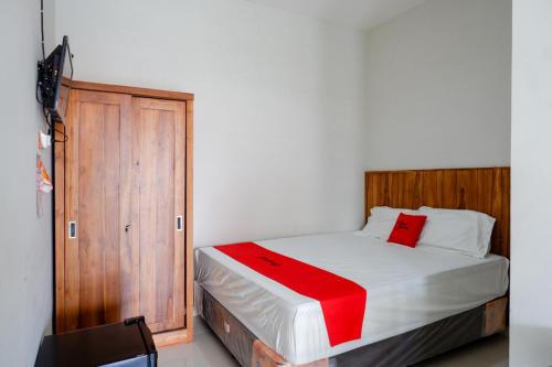 Un dormitorio con una cama con una manta roja. en RedDoorz Plus Syariah near Stasiun Tegal 2, en Tegal