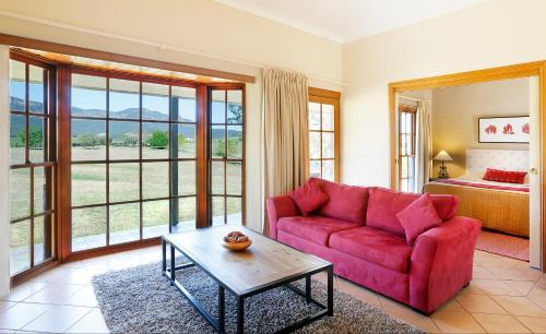 a living room with a red couch and a bed at Berenbell Vineyard Retreat in Pokolbin