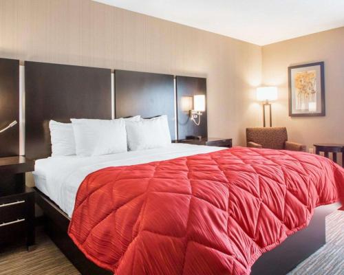 a hotel room with a large bed with a red blanket at Greenstay Inn & Suites Court View in Springfield