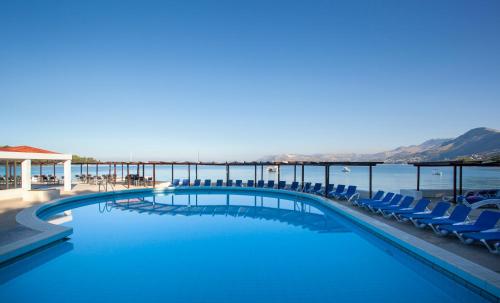 een zwembad met stoelen en de oceaan op de achtergrond bij Remisens Hotel Epidaurus-All inclusive in Cavtat