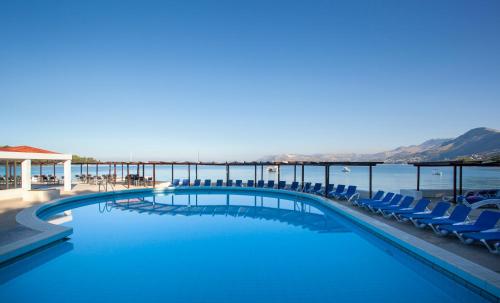 a swimming pool with chairs and the ocean in the background at Remisens Hotel Epidaurus-All inclusive in Cavtat