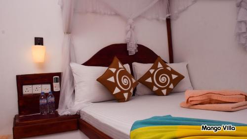 1 dormitorio con 1 cama con almohadas marrones y blancas en Mango Villa Sigiriya, en Sigiriya