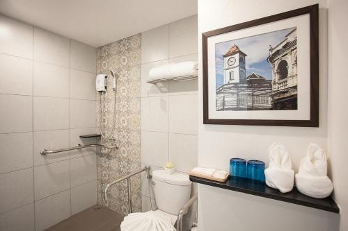 a bathroom with a toilet and a picture of a clock tower at Recenta Suite Phuket Suanluang in Phuket