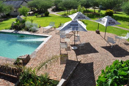 two umbrellas and chairs next to a swimming pool at Etotongwe Lodge in Outjo