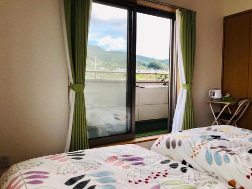 a bedroom with two beds and a large window at Yamanobenomichi teku teku in Tenri