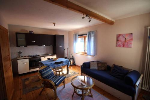 ein Wohnzimmer mit einem blauen Sofa und einer Küche in der Unterkunft Casa Moron in Saint Vincent