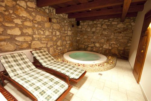 a stone bathroom with two chairs and a tub at Trifecta Udvarház in Tállya