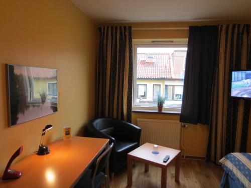 a room with a desk and a chair and a window at Hotel Göingehof in Hässleholm