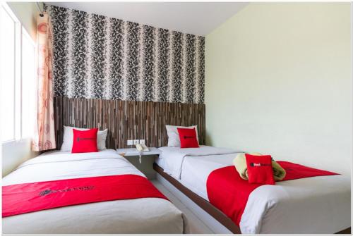 2 camas en una habitación con almohadas rojas en RedDoorz Plus @ Hertasning Area en Makassar