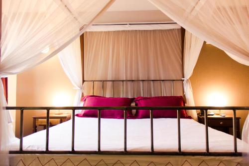 a bedroom with a bed with red pillows at Hotel Bougainviller in Kampala