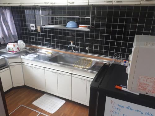 una cocina con fregadero y una pared de azulejos negros en Hostel Amaou, en Oki