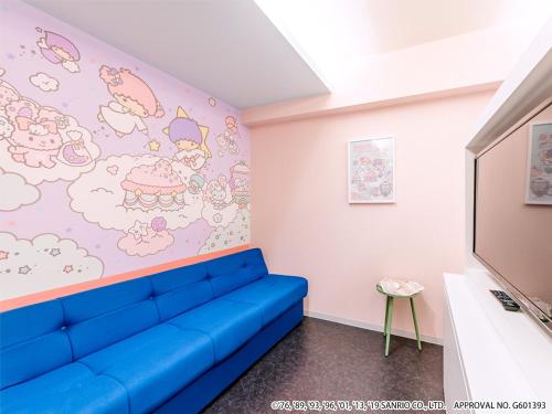 a living room with a blue couch in front of a wall at HOTEL OKINAWA WITH SANRIO CHARACTERS in Naha