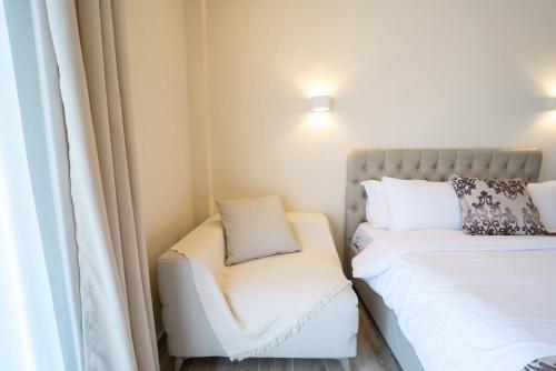 a small room with two beds and a chair at Luxury Plateia Rooms in Perea