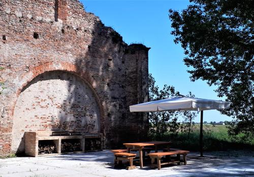 a table with an umbrella next to a brick wall at Agriturismo Casalbergo in Isola della Scala