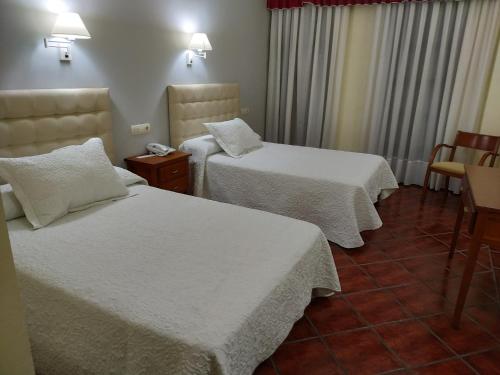 a hotel room with two beds with white sheets at Hotel Cañada Real in Villalpando