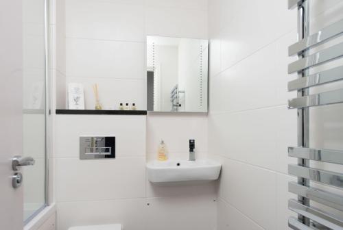La salle de bains blanche est pourvue d'un lavabo et d'un miroir. dans l'établissement Mulberry Flat 2 - Two bedroom 1st floor by City Living London, à Londres