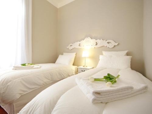 duas camas num quarto com lençóis brancos e toalhas em Mercalli 1 em Milão