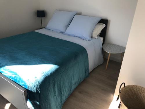 um quarto com uma cama com lençóis azuis e uma mesa em Neuf et haut de gamme au coeur du Pouliguen boutiques port et plage a pied em Le Pouliguen