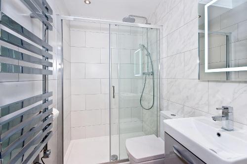 a white bathroom with a shower and a sink at Interlude House D by City Living London in London