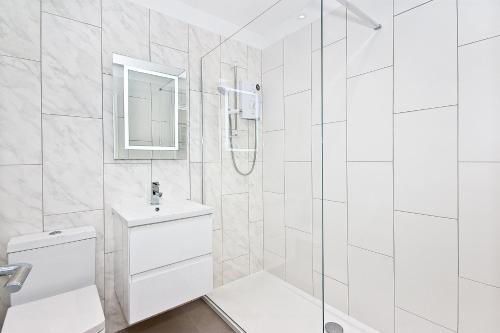 a white bathroom with a shower and a sink at Interlude House E Penthouse by City Living London in London