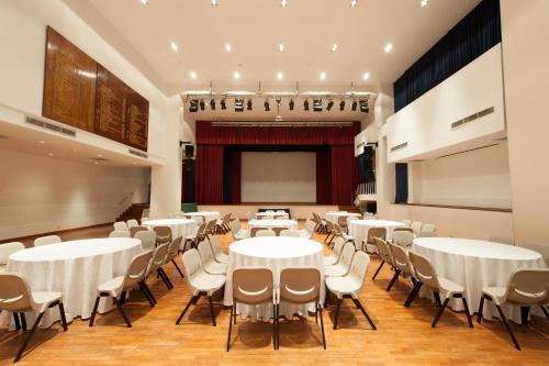 a room with white tables and chairs and a stage at YMCA One Orchard in Singapore