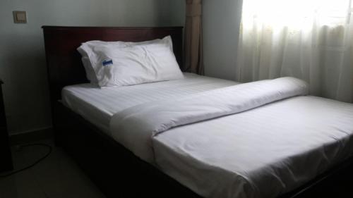 two beds with white sheets and pillows in a room at The Pearl Inn in Koboko