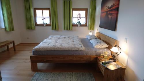 a bedroom with a large bed and two windows at Teisenbergblick in Gschwend