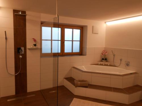 a bathroom with a tub and a glass shower at Teisenbergblick in Gschwend